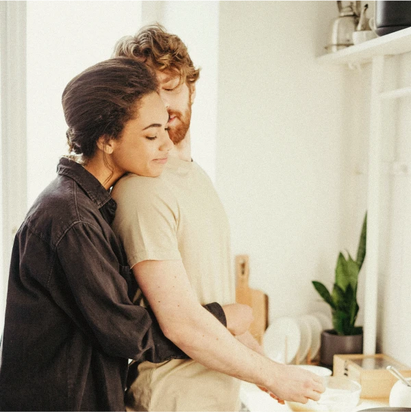 Två personer som kramar varandra i ett kök